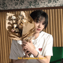 a young man is holding a bouquet of flowers and the caption says feli cumpleanos kou !!