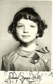 a black and white photo of a little girl in a school dress .