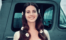 a woman wearing flowers in her hair is smiling in front of a truck