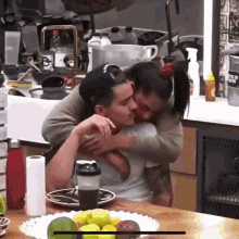 a man and a woman are hugging in a kitchen with a bottle that says ' bottle of water ' on it