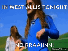 a man in a blue shirt is dancing in a field with a woman in a white shirt .
