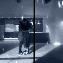 a black and white photo of a couple hugging in a kitchen