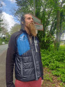 a man with a beard stands in front of a sign that says yann on it