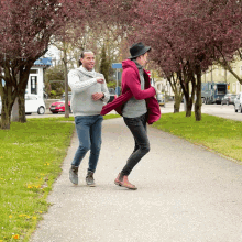 two men are walking down a sidewalk with trees in the background and a sign that says ' downtown ' on it