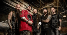 a group of men with dreadlocks and tattoos are posing for a picture in a dark room .