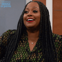 a woman with braids is smiling and wearing a green and black shirt with the words house of payne on the bottom