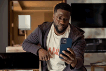 a man wearing a white t-shirt that says why looks at his phone