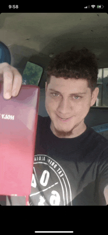 a man in a black shirt is holding a red box that says ' yjoi ' on it