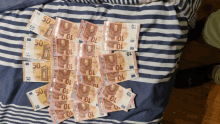 a pile of 50 and 10 euro bills on a striped bedspread