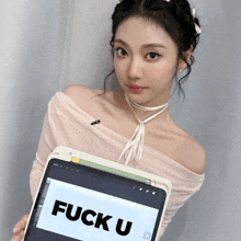 a woman is holding a tablet that says fuck u on it