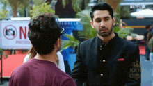 a man in a black suit is shaking hands with another man .
