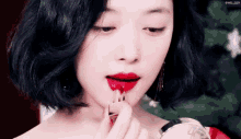 a woman applies red lipstick to her lips