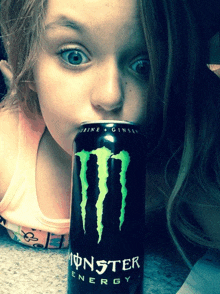 a little girl drinking a can of monster energy