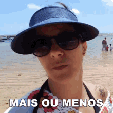 a woman wearing sunglasses and a hat stands on a beach with the words mais ou menos written below her