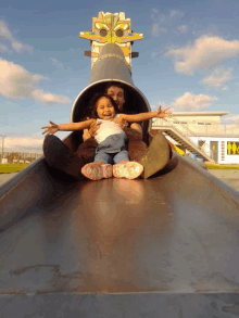 a little girl is going down a slide with her father