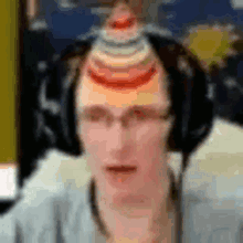 a man wearing headphones and a party hat on his head is looking at the camera .