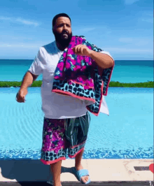 a man standing next to a pool holding a colorful towel