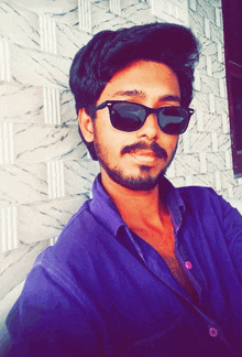 a young man wearing sunglasses and a purple shirt poses for a picture