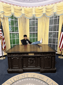 a man sits at the president 's desk with his feet up