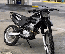 a black honda dirt bike is parked on the side of the road