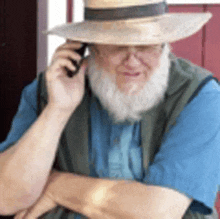 a man with a beard wearing a hat is talking on a cell phone .