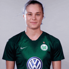 a woman wearing a green shirt with a vw logo on the front