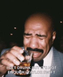 a bald man with a mustache is drinking from a shot glass and crying