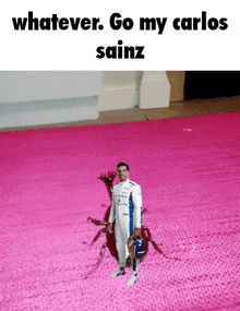 a man in a racing suit is standing on a pink carpet and holding a helmet