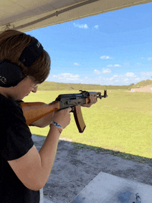 a man wearing ear muffs is shooting a rifle