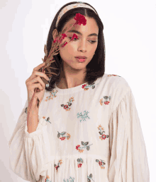 a woman in a white dress is holding flowers in her hair