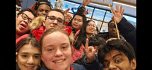 a group of young people are posing for a picture and one girl is giving the peace sign