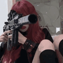 a girl with red hair is kneeling down holding a gun .