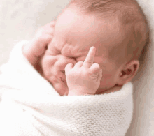 a baby is wrapped in a white blanket and making a middle finger gesture