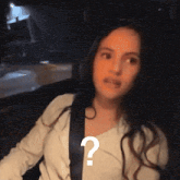 a woman is wearing a seat belt and has a question mark on her chest