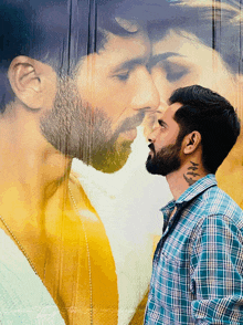 a man with a tattoo on his neck is standing in front of a poster of a man and woman kissing