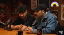 two men are sitting at a table in front of microphones and a sign that says ' bonne toi '