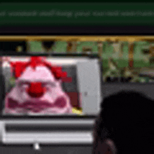 a person is sitting in front of a computer screen with a clown on it .