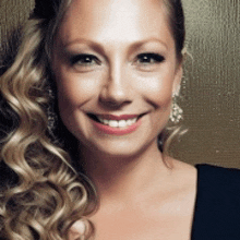 a woman with curly hair is smiling and wearing a black top