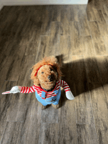 a small brown dog wearing a chucky costume is standing on a wooden floor