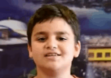 a young boy is standing in front of a wall with a picture of a boat on it .