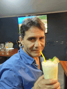 a man in a blue shirt is drinking a smoothie with a straw