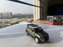 a toy car with a roof rack is sitting on a table in front of a window