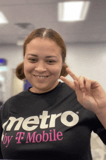 a woman wearing a black metro by t mobile shirt giving a peace sign