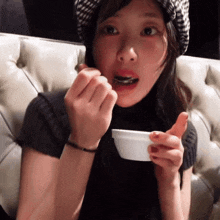 a woman sitting on a couch eating from a bowl