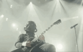 a man in a gas mask is playing a guitar and singing into a microphone on a stage .