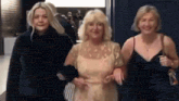 three women are standing next to each other and smiling .