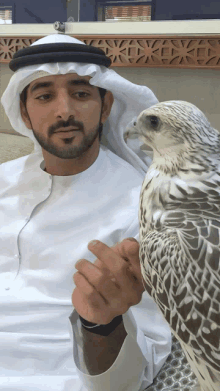 a man in a white robe is holding a white and brown bird