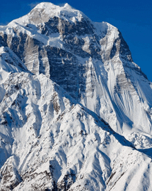 a large snow covered mountain with a blue sky in the background