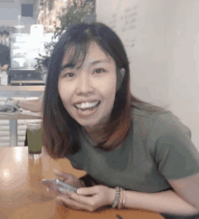 a woman sitting at a table with a cell phone in her hand