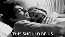 a black and white photo of a man and a woman hugging each other in bed .